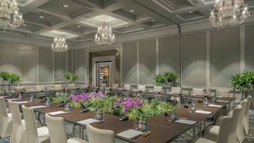 A conference room with a long table, chairs, and chandeliers.