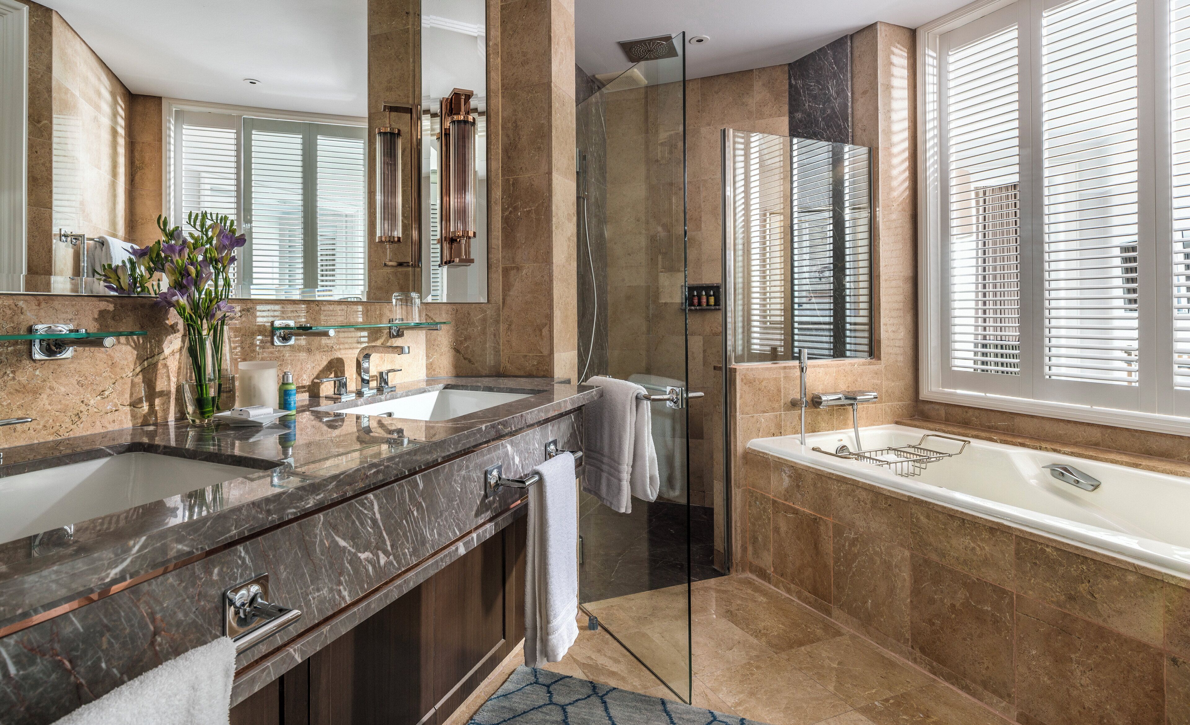 A modern bathroom with a glass-enclosed shower, a large bathtub, and a vanity with a marble countertop.