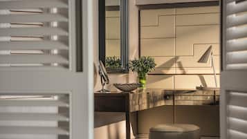 A modern bathroom with a vanity, mirror, and a potted plant.