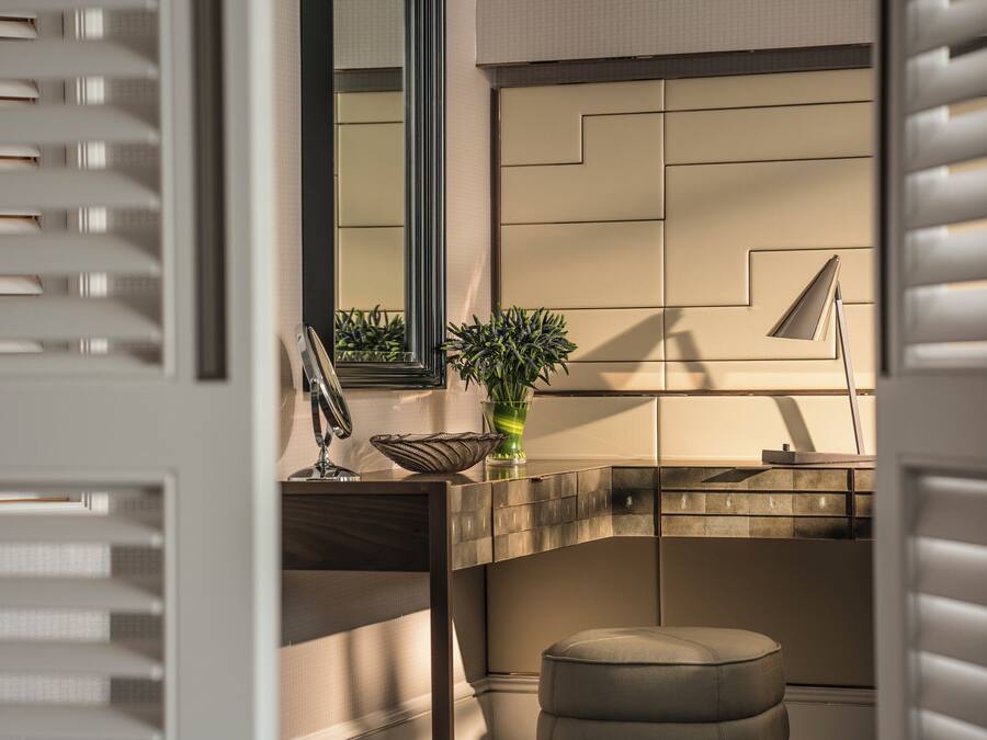A modern bathroom with a vanity, mirror, and a potted plant.