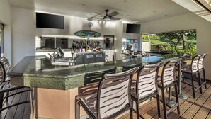 Une cuisine moderne avec un coin bar, une piscine et un espace salon extérieur.
