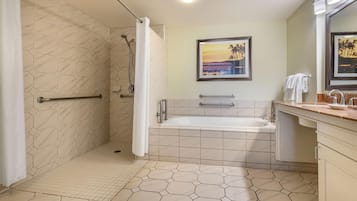 Un baño con ducha, bañera y tocador con espejo.