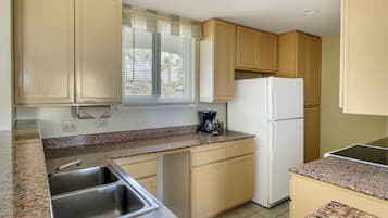 Eine Küche mit Granit Arbeitsplatten, einer Edelstahl-Spüle, einem weißen Kühlschrank und beigen Küchenschränken.