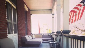 Eine überdachte Veranda mit einer Couch, Stühlen und einer amerikanischen Flagge.