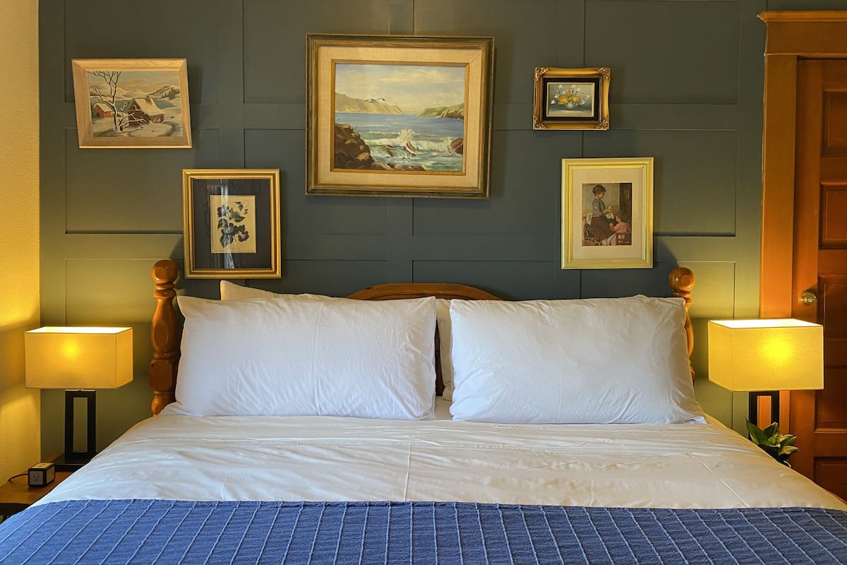 A hotel room with a large bed, two bedside lamps, and four framed pictures on the wall.