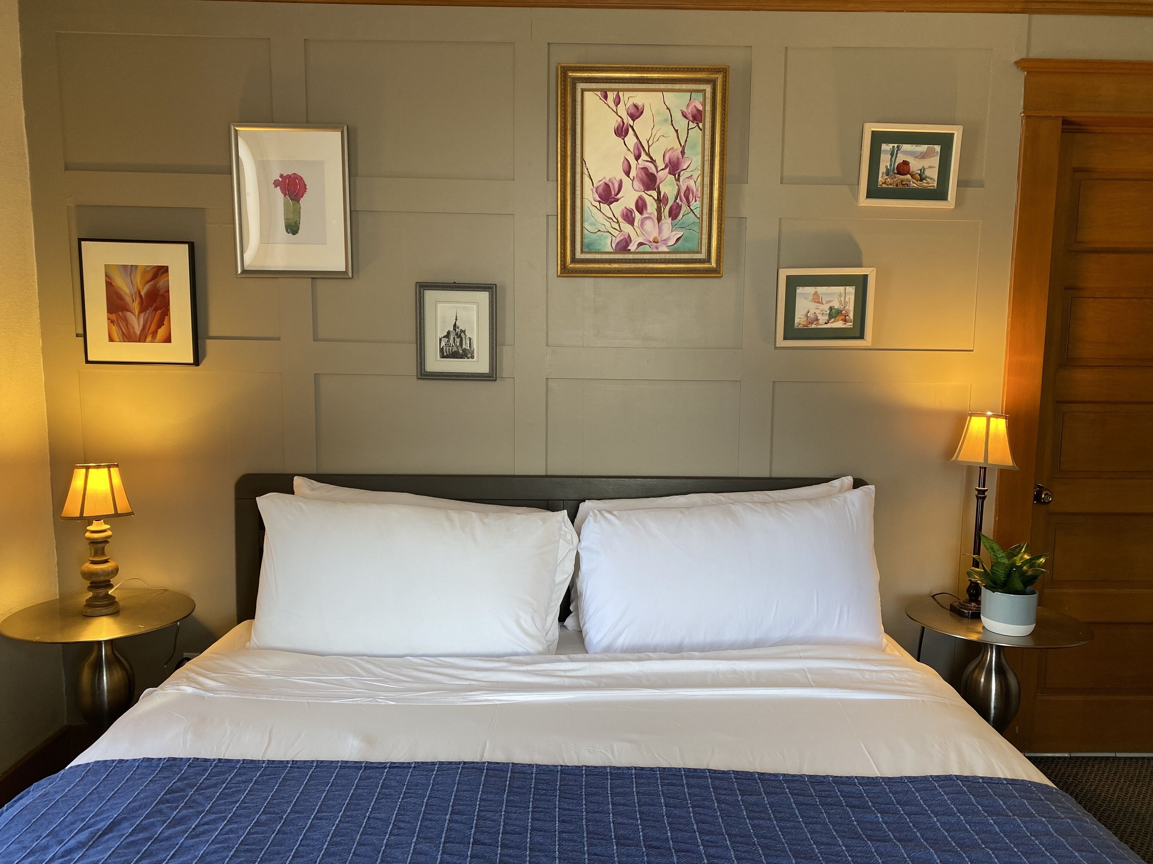 A hotel room with a bed, two bedside tables, and wall-mounted artwork.