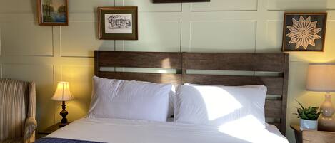 Una cama bien hecha con un edredón azul, un cabecero de madera y obras enmarcadas en las paredes.
