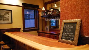 Eine Bar mit Holztresen, Hockstühlen und einem Kreidetafel-Schild, das eine Eröffnung ankündigt.