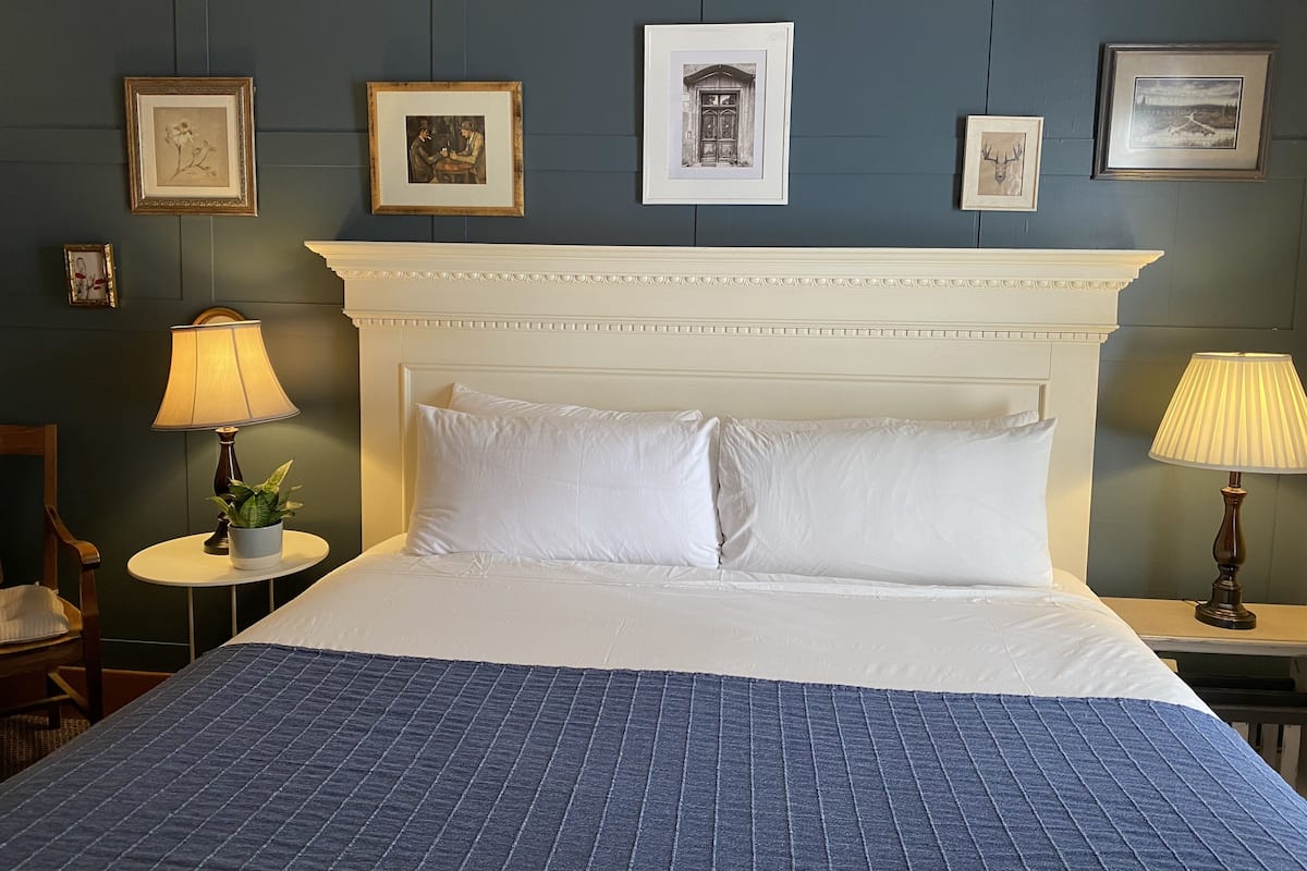 A hotel room with a large bed, two bedside tables, a chair, and framed pictures on the wall.