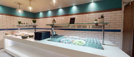 A buffet area with various food items, a glass display case, and a sign about food allergens.