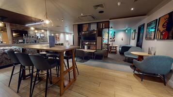 A modern interior with a wooden bar area, seating arrangements, and artwork on the walls.