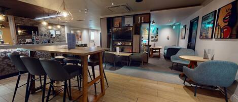 A modern interior with a wooden bar area, seating arrangements, and artwork on the walls.