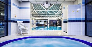 Une piscine intérieure offrant une vue dégagée sur l’espace piscine, une chaise blanche et un mur carrelé avec une bande bleue.