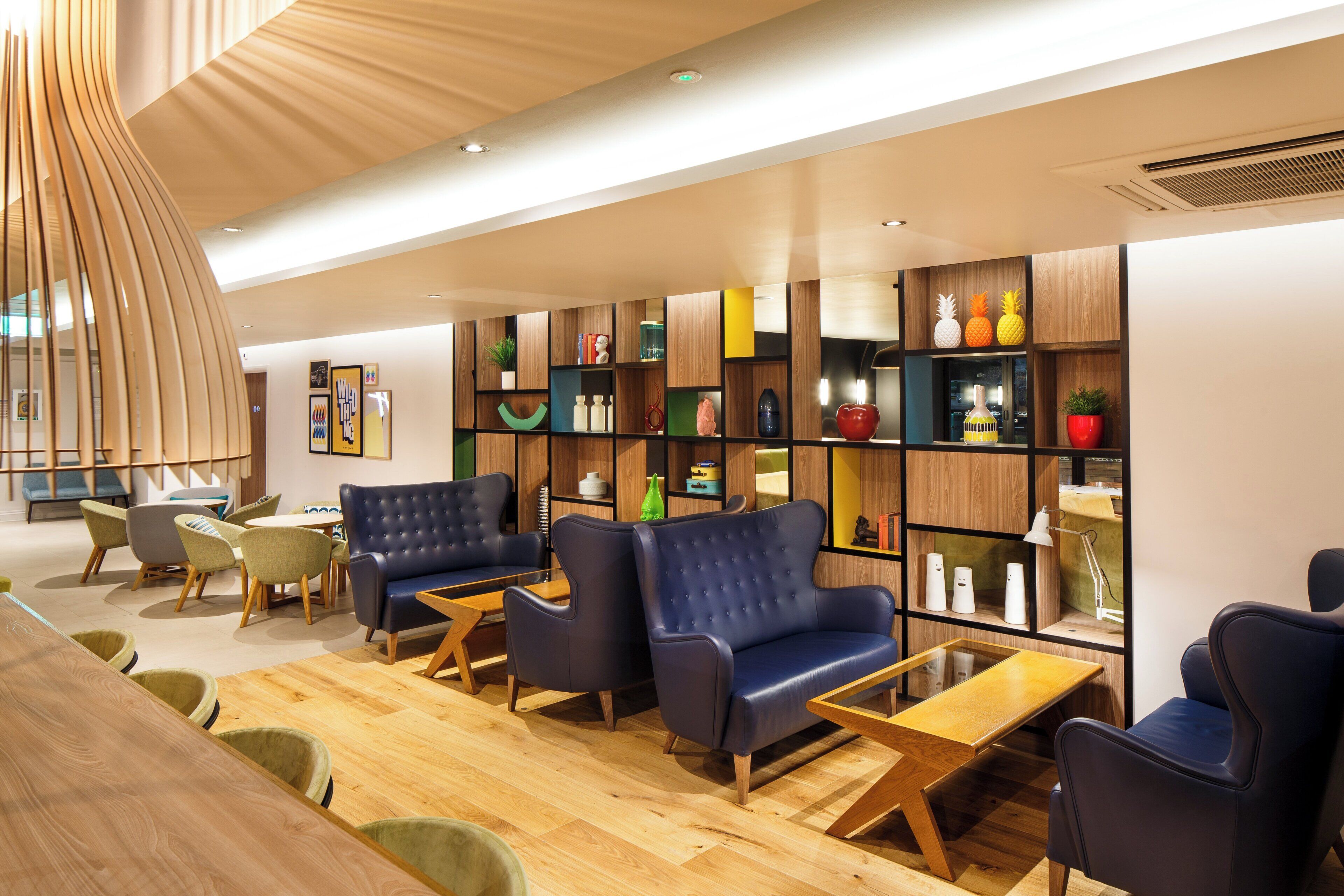 A modern interior with a wooden floor, leather armchairs, a wooden coffee table, and a bookshelf with various decorative items.