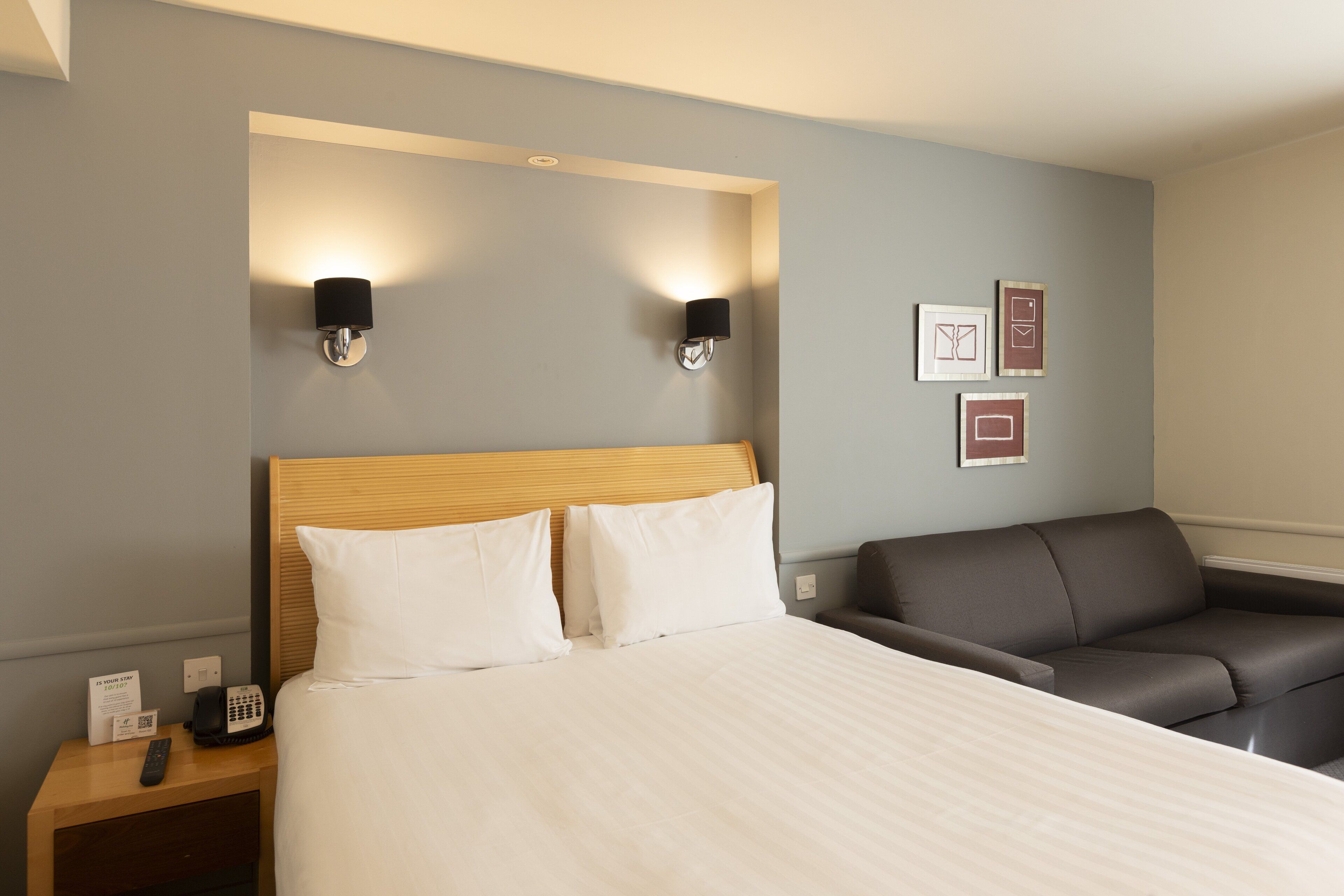 Une chambre d’hôtel avec un lit, une table de chevet avec un téléphone et un canapé.