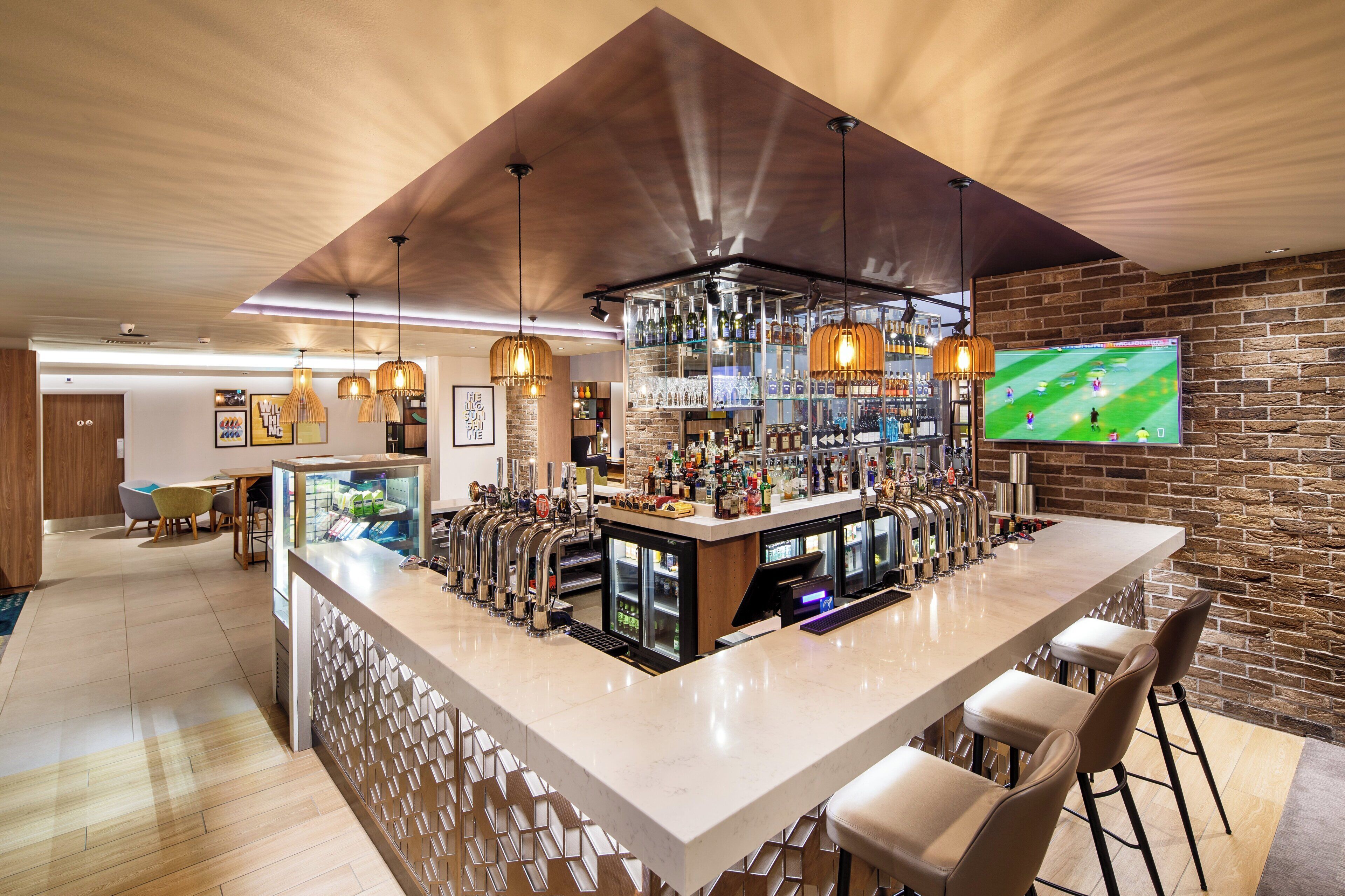 A bar area with multiple taps, a television screen, and a brick wall.