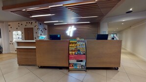 Un comptoir d’accueil doté d’un écran numérique, un panneau d’affichage présentant des brochures de voyage et un design moderne au niveau du plafond.