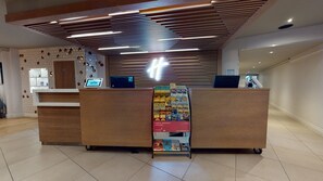 Un comptoir d’accueil doté d’un écran numérique, un panneau d’affichage présentant des brochures de voyage et un design moderne au niveau du plafond.