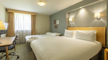 A hotel room with two beds, a desk, and a chair.