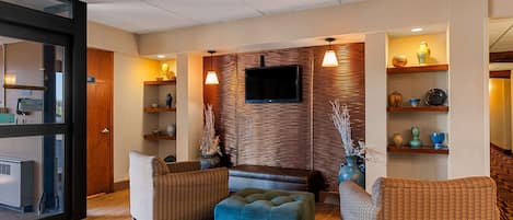 Un salon moderne doté d’un téléviseur à écran plat, de canapés en osier, d’un pouf bleu et de lambris en bois.