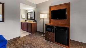A hotel room with a kitchenette, a flat-screen TV mounted on a wooden cabinet, a microwave, and a small refrigerator. - Best Western Bridgeview Hotel (Superior)