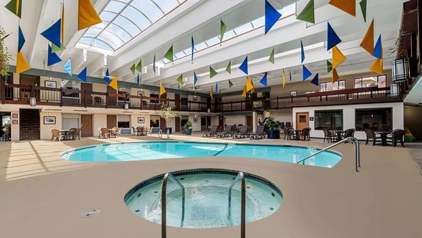 An indoor swimming pool with a sunroof, surrounded by lounge areas and a multi-level balcony. - Best Western Bridgeview Hotel (Superior)