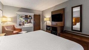 A hotel room with a large bed, two bedside lamps, a flat-screen TV, a wooden cabinet, and a window with a view of the outdoor area. - Best Western Bridgeview Hotel (Superior)
