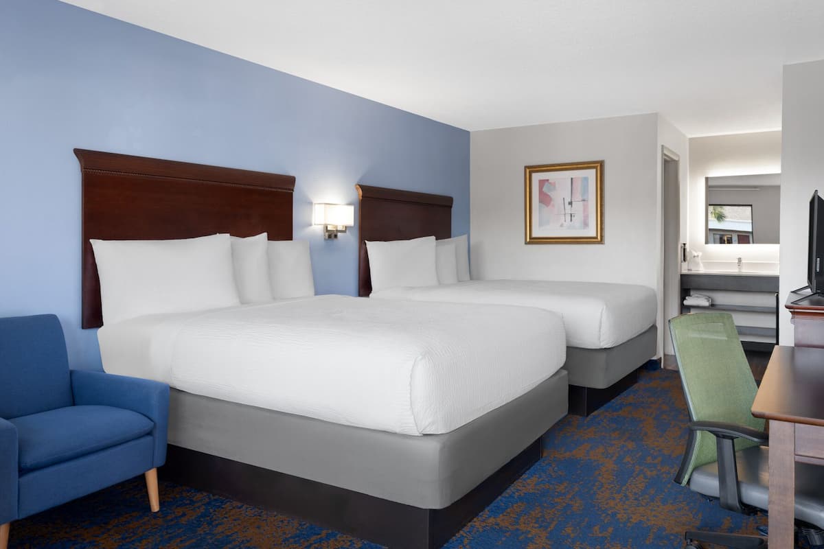Une chambre d’hôtel avec un grand lit, deux tables de chevet, une chaise, un bureau et un téléviseur.