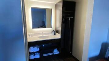 Un baño pequeño con lavamanos integrado, espejo y suelo de madera oscura.