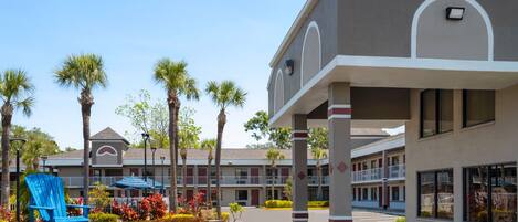 A hotel with a central courtyard, palm trees, and a blue chair.
