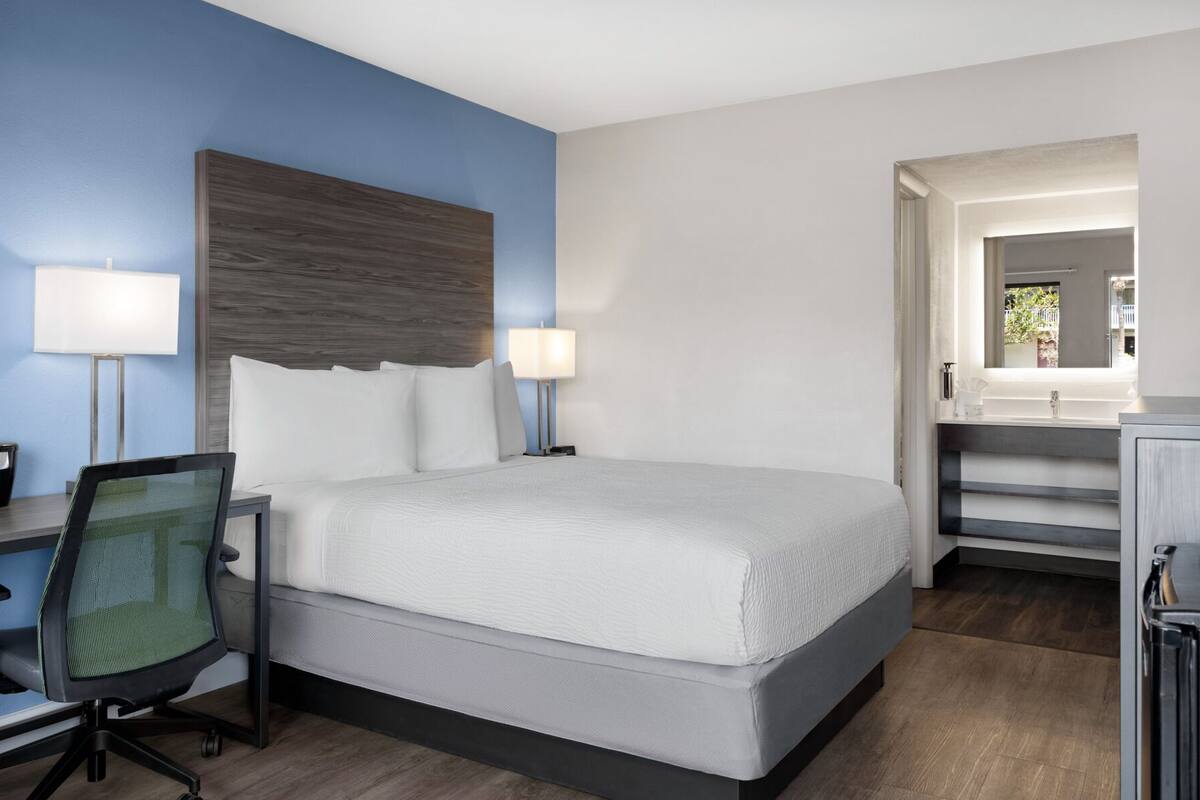 Une chambre d’hôtel avec un lit, un bureau, une chaise et une vue sur l’extérieur.