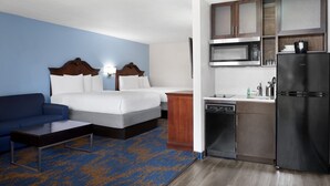 Une chambre d’hôtel avec un lit, un canapé, une kitchenette et une moquette bleue.