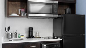 Une cuisine moderne équipée d’un four à micro-ondes en acier inoxydable, d’un réfrigérateur noir et d’un lave-vaisselle encastré.