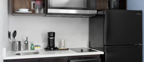 A modern kitchen with a stainless steel microwave, black refrigerator, and built-in dishwasher.