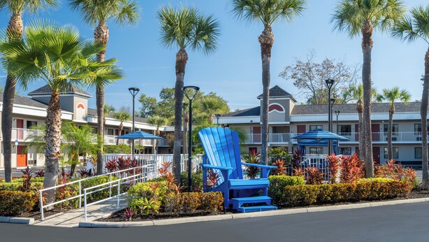 Un hôtel doté d’une piscine, de palmiers et d’un fauteuil Adirondack bleu.