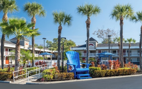 A hotel with a pool area, palm trees, and a blue Adirondack chair.