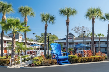 A hotel with a pool area, palm trees, and a blue Adirondack chair.