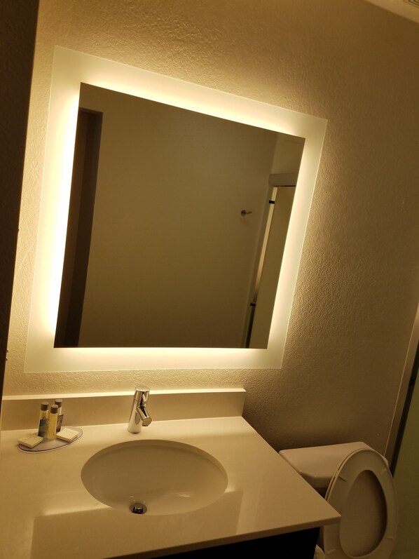 A bathroom with a white sink, a mirror, and a toilet.