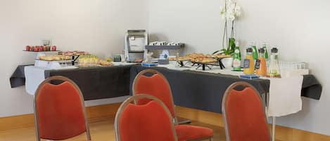 A conference room with a buffet table, red chairs, and a coffee machine.