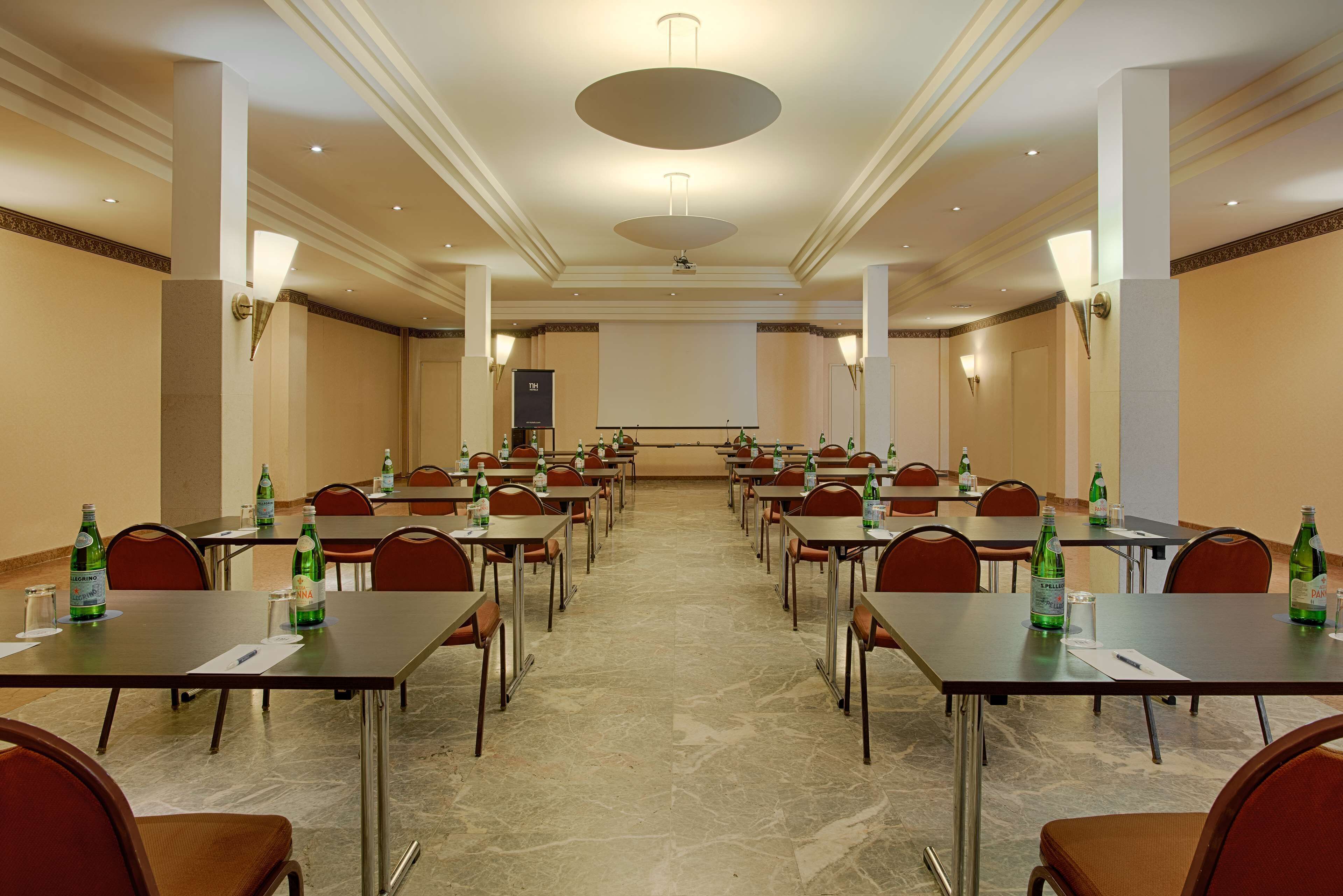 A conference room with tables and chairs, equipped with water bottles and glasses.