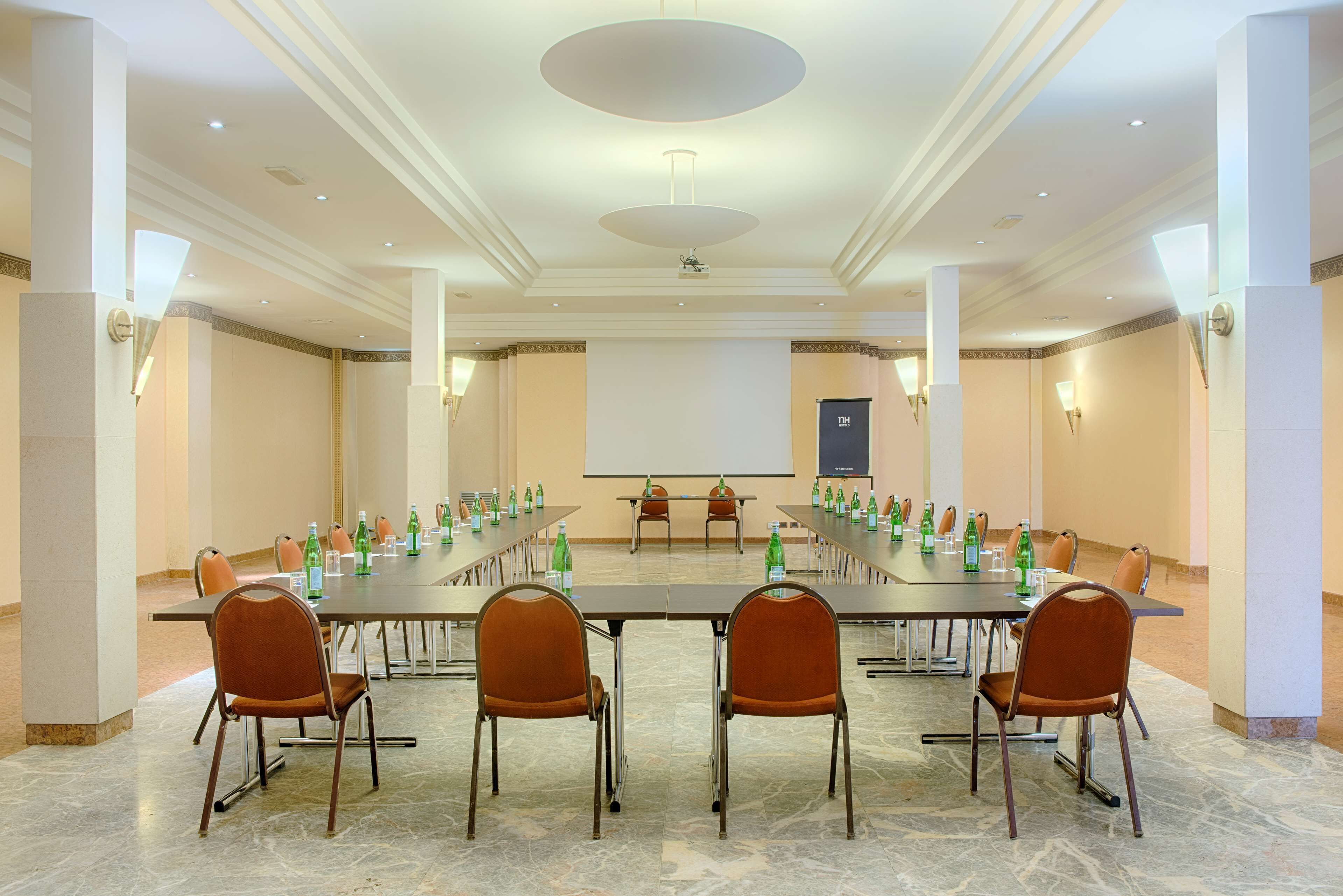 Une salle de conférence équipée d’une longue table, de nombreuses chaises et d’un écran de projection.