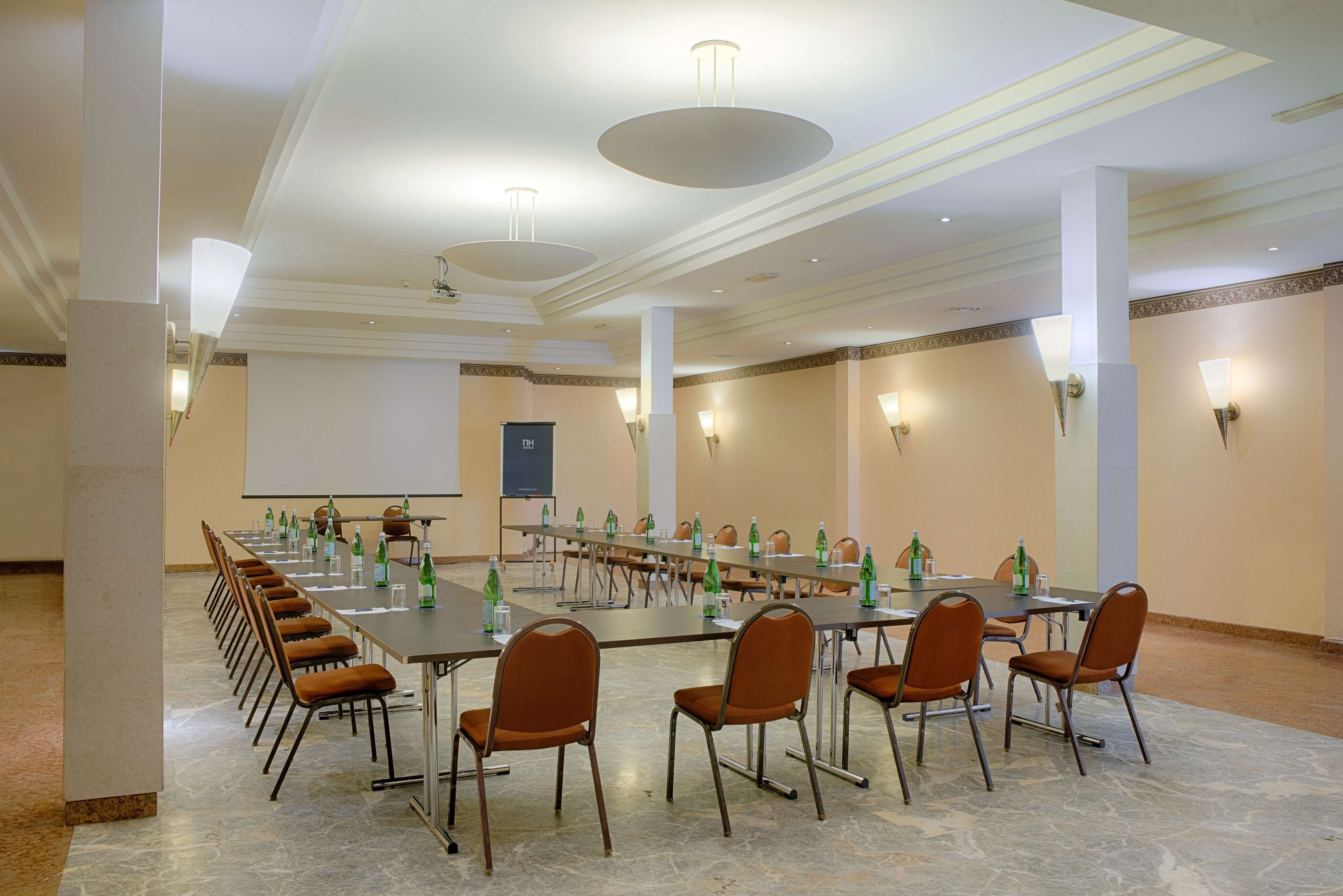 Un salón de conferencias con una larga mesa, sillas y una pantalla para proyector.
