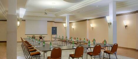 A conference room with a long table, chairs, and a projector screen.