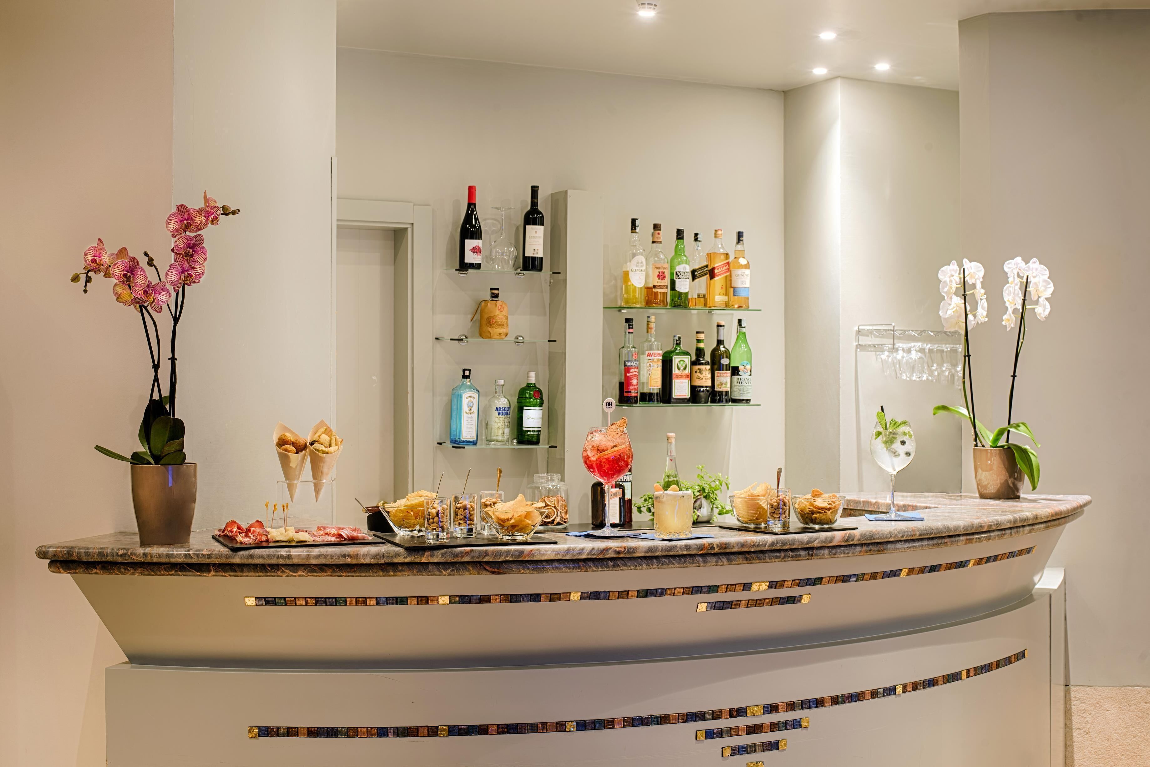 Een bar met een gebogen toonbank, diverse flessen, glazen en een assortiment aan gerechten.