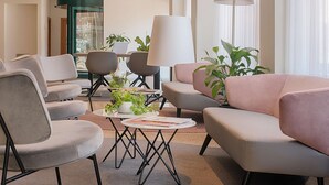 Una sala de estar moderna con un sofá, sillas, una mesa baja con plantas y un comedor con una lámpara.