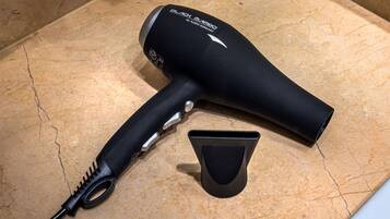 A hairdryer and its attachments on a marble countertop.