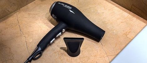 A hairdryer and its attachments on a marble countertop.