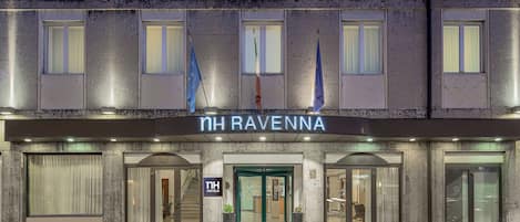 The exterior of NH Ravenna hotel with a modern facade, large windows, and a prominent entrance.