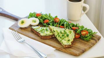 A breakfast setting with toast, eggs, salad, and a cup of coffee on a white table.