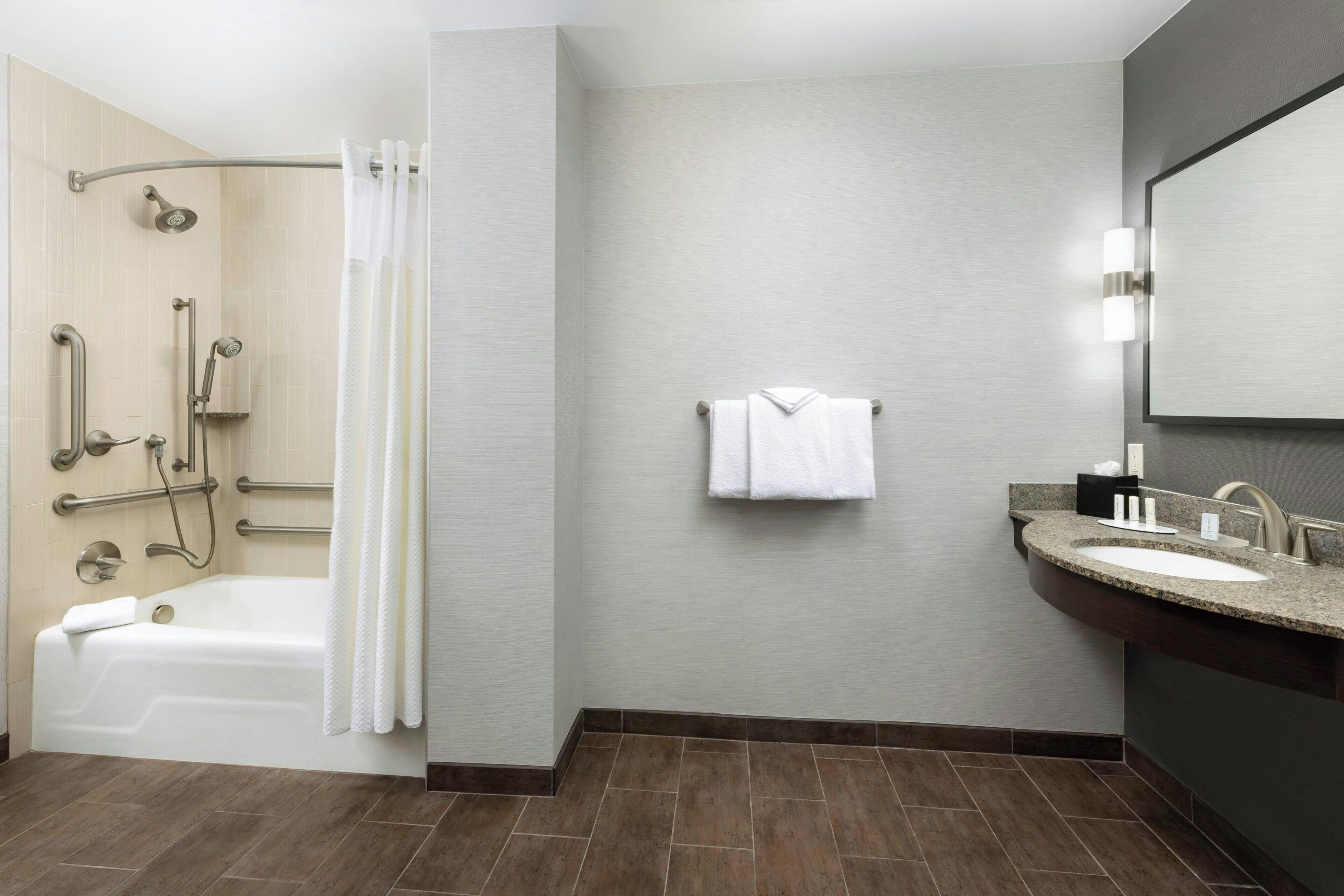 A modern bathroom with a bathtub, shower, and vanity.
